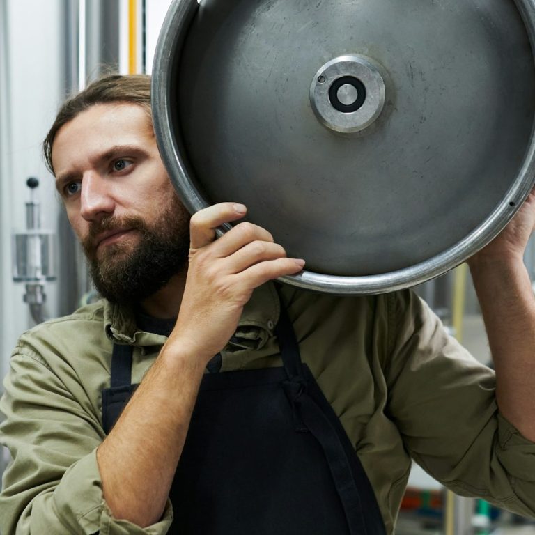 Fassbier und Flaschenbier Mann trägt ein Bierfass in einer Brauerei – Symbolbild für Fassbier
