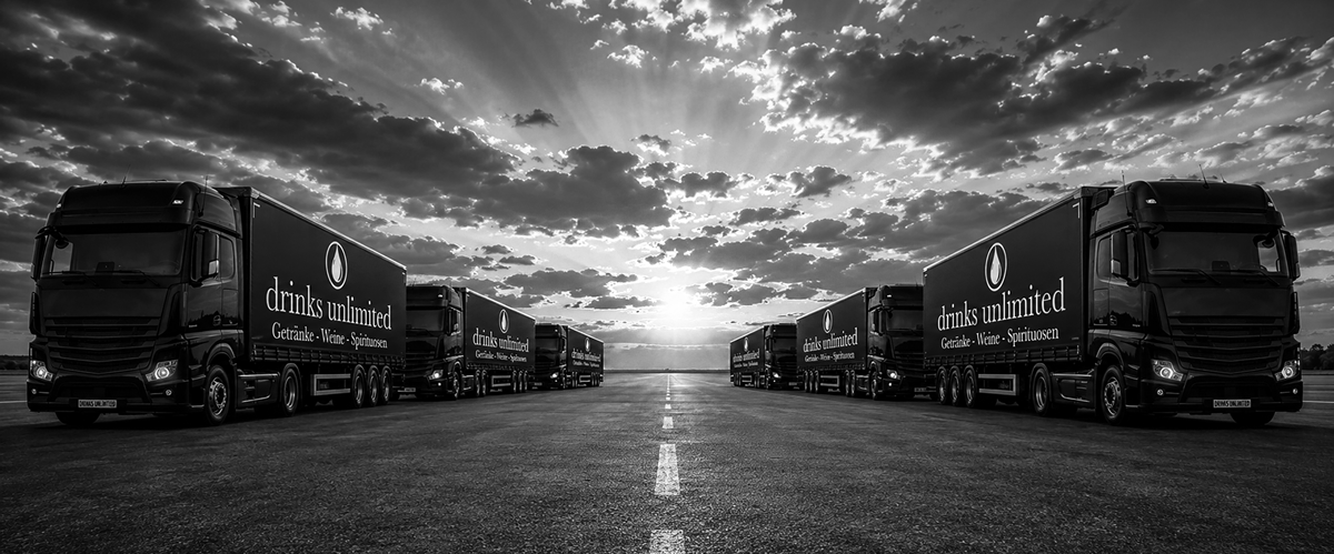 drinks unlimited – Getränke, Weine und Spirituosen Schwarz-weißes Logistikmotiv mit LKW und drinks-unlimited-Schriftzug